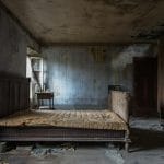 Jaki materac sprężynowy wybrać po 40-tce? Wsparcie lędźwi i regeneracja Zniszczona sypialnia z obdrapanymi ścianami i starym łóżkiem sprężynowym