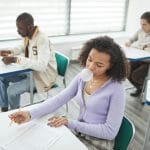 Różnorodna grupa studentów piszących test w nowoczesnej sali