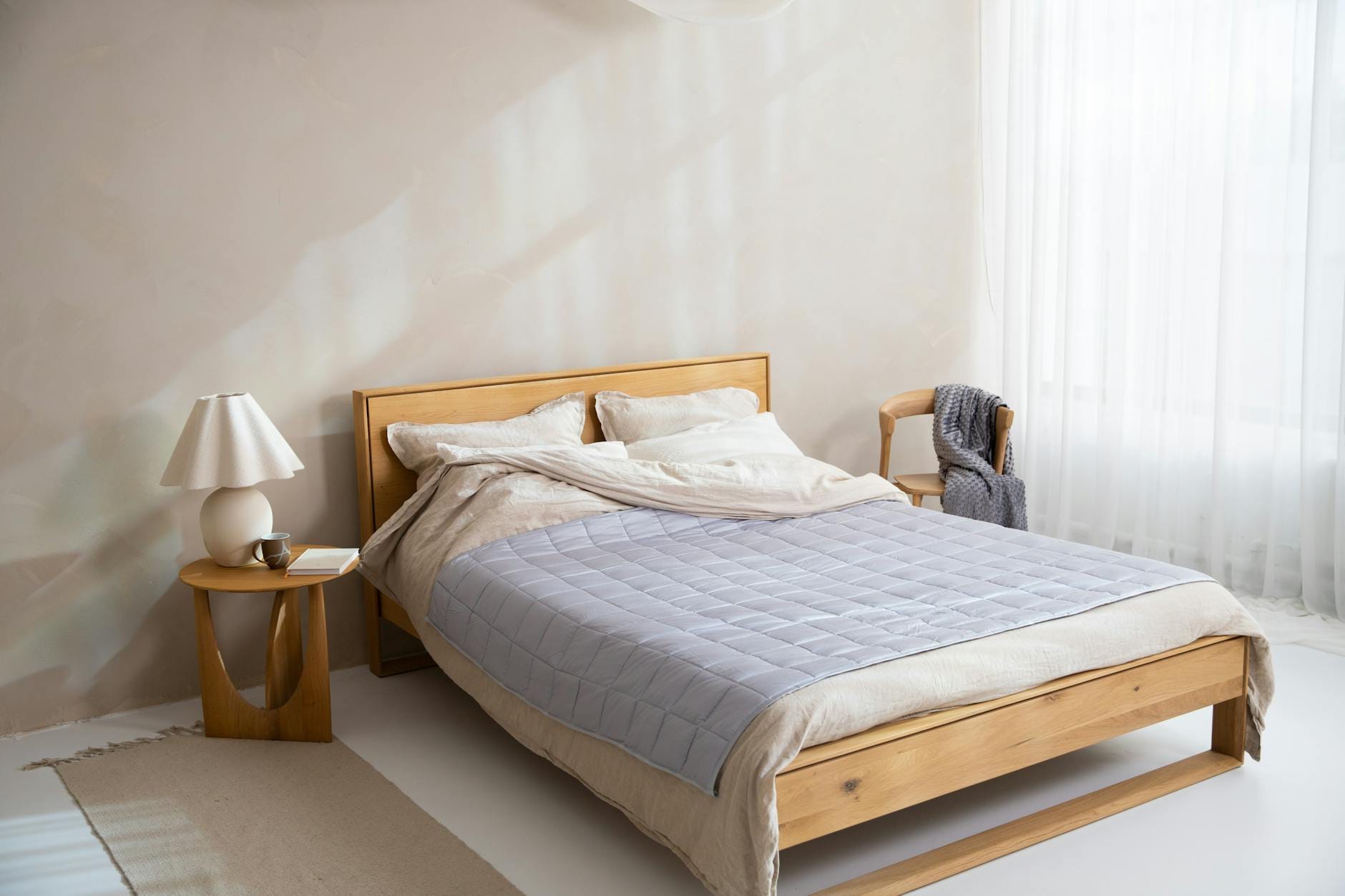 Jasna minimalistyczna sypialnia z drewnianym łóżkiem i pościelą