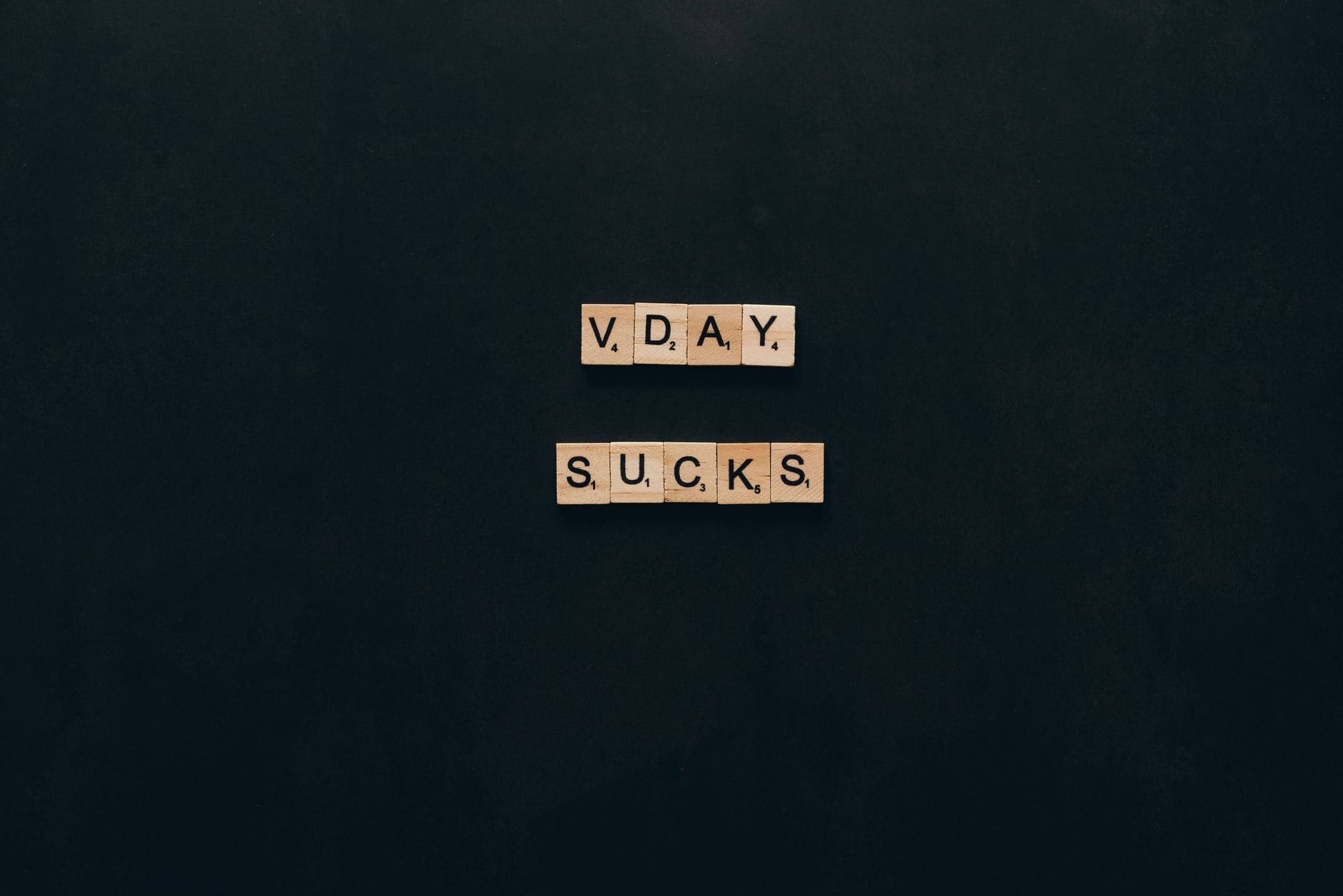 Kafelki scrabble z napisem V. Day Sucks na czarnym tle