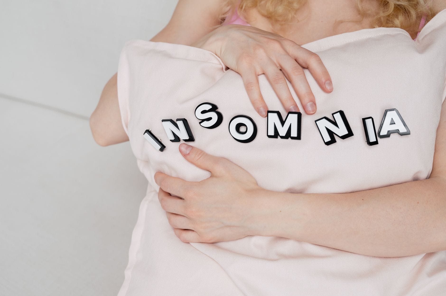 Zbliżenie kobiety przytulającej poduszkę z napisem insomnia