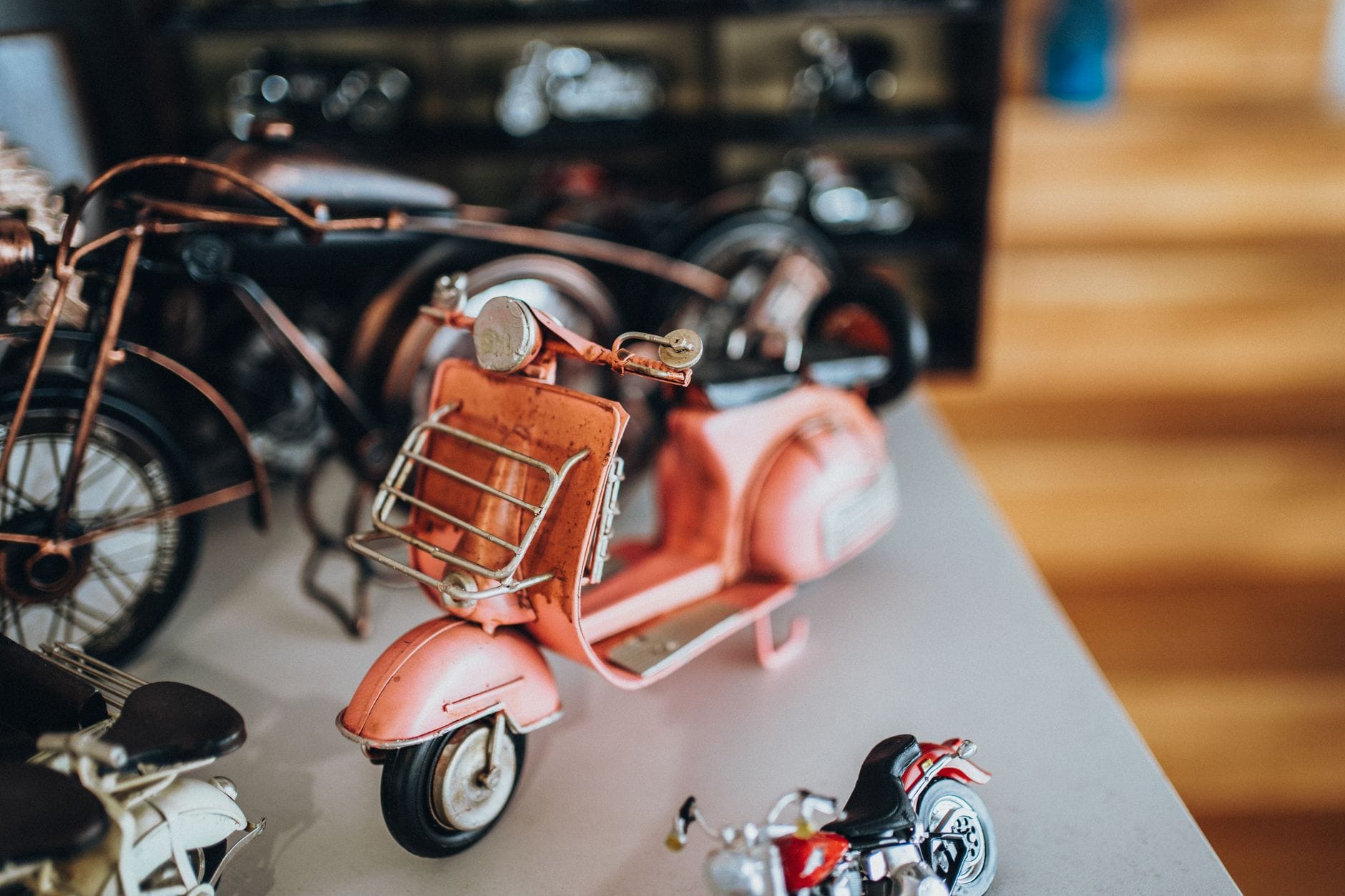 Zbliżenie na różowy skuter zabawkowy wśród miniaturowych motocykli vintage Zbliżenie na różowy skuter zabawkowy wśród miniaturowych motocykli vintage