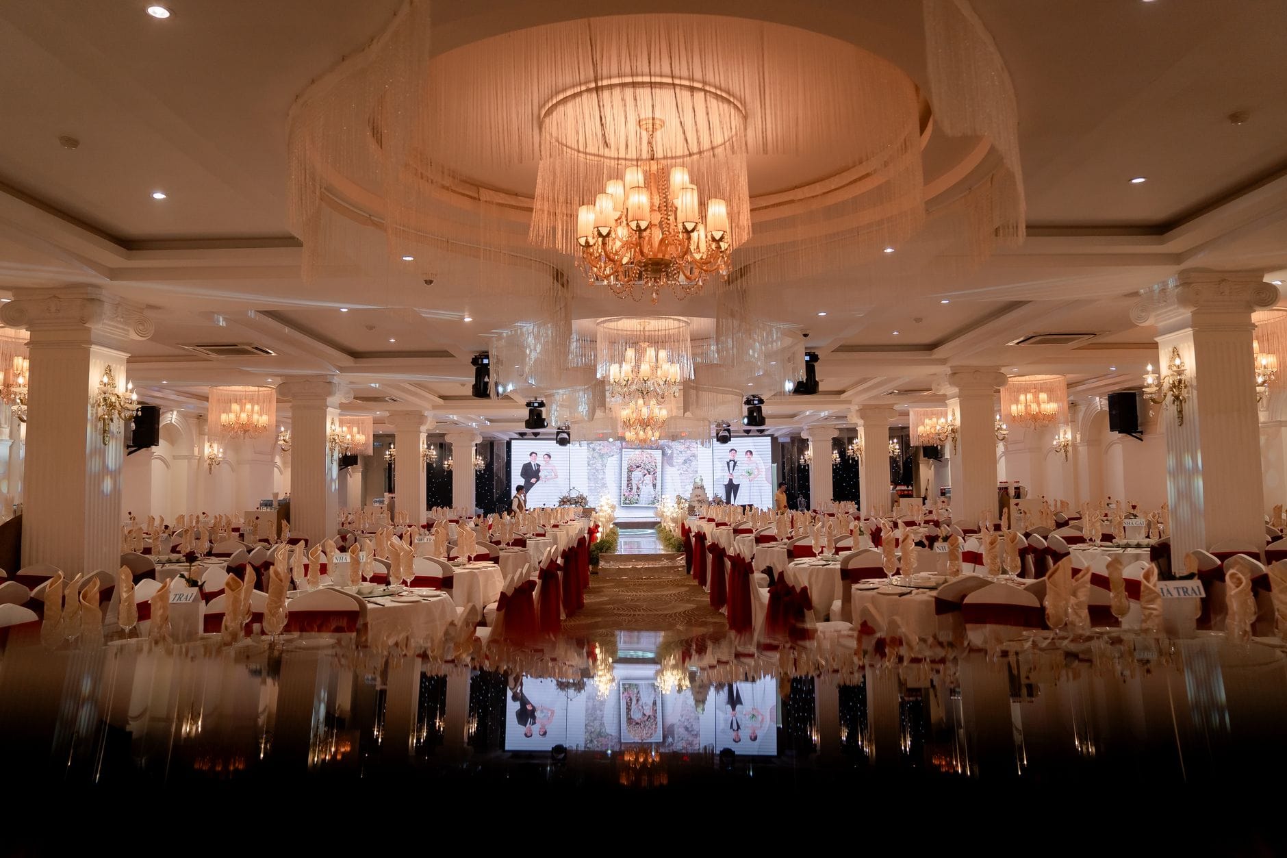 Elegancka sala balowa z żyrandolami przygotowana na przyjęcie weselne