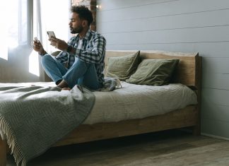 Mężczyzna na łóżku korzysta ze smartfona podczas zakupów online